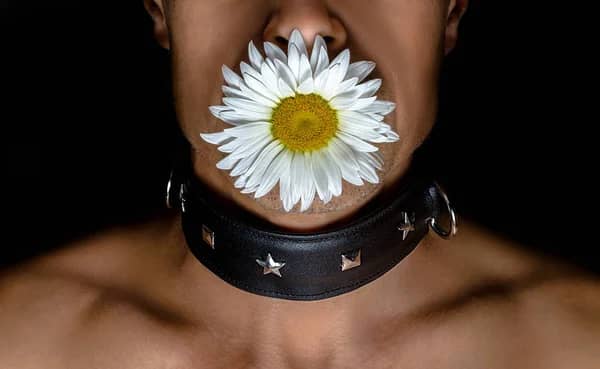 Mujer con una flor en la boca.